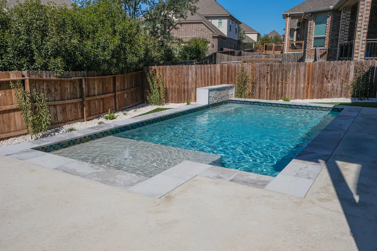 Rectangular backyard pool framed by planting and wood fencing