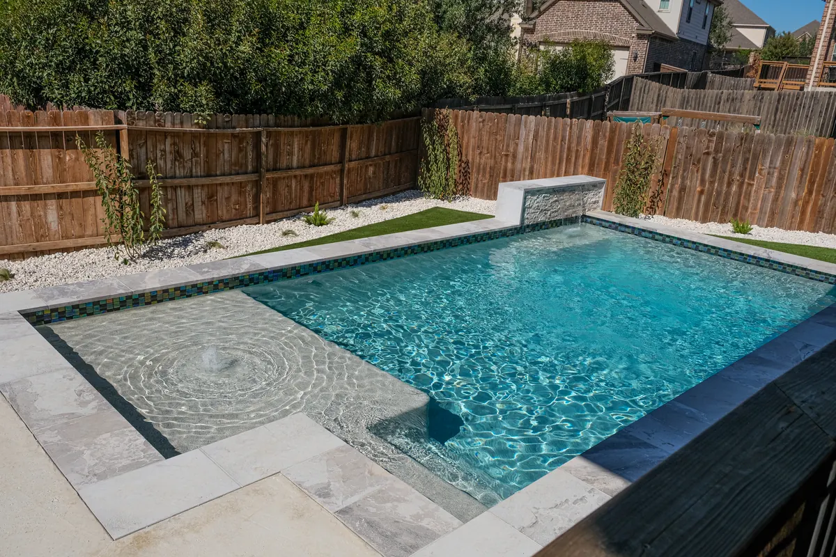 Pool with mosaic waterline, sun shelf and a raised waterfall