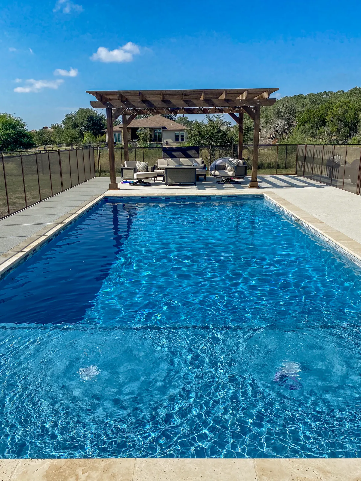 View along the pool toward the pergola and outdoor lounge